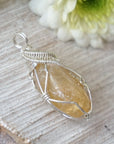 Side angle of wire wrapped citrine pendant in sterling silver showing artisan craftsmanship and stone depth