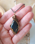 Blue tiger's eye necklace for men in hand for size reference – natural polished stone, antique bronze copper wire, masculine design.