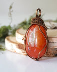 Left angle close-up of carnelian necklace – artisan wire wrapping, natural orange stone, Virgo birthstone pendant by Designs by Nature Gems.