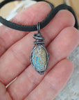 Raw opal pendant for men shown in hand for size reference – natural Ethiopian fire opal, antiqued sterling silver wire, black leather cord.