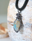 Left angle close-up of men's opal necklace – highlighting unique wire-wrapped artistry, Ethiopian fire opal, black leather cord.