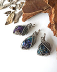 Three peacock ore pendants for men – showing natural variation in size, shape, and iridescent colours, white gold copper wire wrapping.