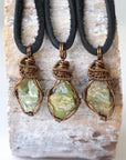 Three raw peridot pendants for men – showing natural variation in size, shape, and green shade, black leather cord.