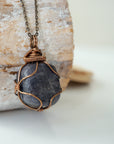 Right angle close-up of sapphire necklace – detailed artisan bronze copper wire wrapping, raw blue sapphire, handcrafted pendant.