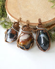 Three raw sardonyx pendants – showing natural variation in size, shape, and color pattern, handcrafted unisex birthstone jewelry.
