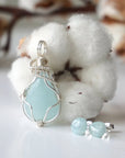Detailed front angle of aquamarine jewelry set, showing wire wrapped pendant and minimalist stud earrings, soft silver finish, genuine aquamarine