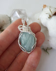 Aquamarine pendant in hand for size reference, genuine polished raw aquamarine, soft silver over copper wire wrapping