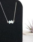 Focused left-side close-up of sterling silver aquamarine and pearl bar necklace on jewelry display