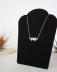 Left angle view of aquamarine and pearl bar necklace in 925 sterling silver on jewelry display