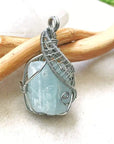 Close-up of aquamarine pendant front, raw gemstone in detailed artisan dark silver wire wrapping