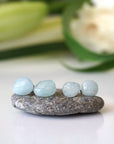 Two pairs of aquamarine stud earrings showing natural variation in size, shape, and blue color, raw stones, sterling silver