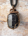 Detailed view of raw black tourmaline necklace on black leather cord, artisan wire wrapped pendant by Designs by Nature Gems.