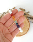 Chakra beaded stretch bracelet in hand for size reference, natural white howlite, amethyst, lapis lazuli, green aventurine, citrine, orange carnelian, red carnelian beads