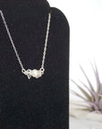 Focused left-side close-up of sterling silver clear quartz and pearl bar necklace on jewelry display