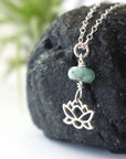 Left angle detail of emerald and lotus necklace for women with natural faceted emerald bead and minimalist lotus charm