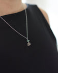 Emerald and lotus necklace for women worn on female model with natural emerald bead and sterling silver lotus pendant