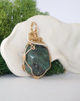 Right angle detail of emerald pendant for women showing natural polished-raw emerald and artisan 14k gold filled and sterling silver wrapping