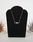 Emerald and freshwater pearl bar necklace in 925 sterling silver on jewelry display, front view
