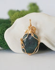 Back angle detail of emerald and freshwater pearl pendant, showing wire wrapping and natural stone