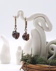 Front angle of garnet drop earrings hanging on a jewelry display, showcasing wire-wrapped design.