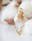Left angle view of handmade Herkimer diamond pendant highlighting warm gold copper wire artistry.