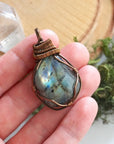 Labradorite pendant held in hand showing stone size — 80 to 100 carat polished-raw labradorite in antique bronze wire wrap