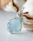 Light blue topaz pendant in sterling silver resting beside a cotton boll