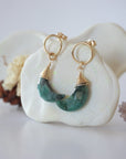 Side angle view of Emerald Moon Open Circle Stud Earrings hanging on jewelry display, minimalist 14k gold filled wire wrap, limited edition.