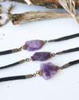 Three men’s amethyst bracelets showing natural variation in amethyst stone color, size, and shape, black leather cord, antique bronze wire wrap