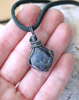 Raw sapphire pendant held in hand to show size — antiqued 925 sterling silver wire wrap, men's handcrafted crystal necklace by Designs by Nature Gems