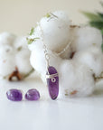 Front view of minimalist amethyst jewelry set with polished raw amethyst pendant necklace and amethyst stud earrings in silver setting