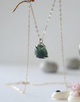 Side angle view of minimalist emerald necklace showing 925 sterling silver prong setting and natural raw emerald.