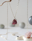 Close front view of minimalist raw garnet pendant in sterling silver claw setting on a sterling silver chain