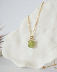 Side angle detail of minimalist raw peridot pendant — gold vermeil four-prong setting showing natural stone texture and depth, dainty August birthstone necklace for women