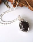 Natural garnet necklace with raw crystal pendant on silver plated brass cable chain laying flat