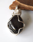 Back view of raw garnet pendant highlighting intricate silver plated copper wire wrap craftsmanship