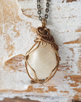 Close-up of natural polished-raw moonstone necklace, hand wire wrapped in antique bronze finish over copper (June birthstone).