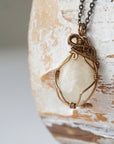 Left angle close-up of natural moonstone pendant necklace, antique bronze wire wrapped setting showing handcrafted detail.