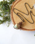 Natural opal pendant on antique bronze chain laying flat, handcrafted jewelry by Designs by Nature Gems.