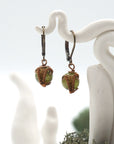Close-up of handcrafted peridot drop earrings with antique bronze copper wire wrapping.