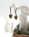 Front angle of peridot drop earrings hanging on a jewelry display, wire-wrapped design.