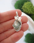 Peridot and freshwater pearl pendant necklace in hand for size reference, silver wire wrapped, handcrafted gemstone jewelry