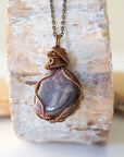 Back angle of men's large polished raw ruby pendant displaying antique bronze wire wrapping craftsmanship — handmade artisan crystal jewelry, nickel-free