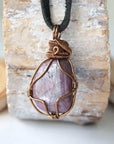Back angle of men's large polished raw ruby pendant displaying antique bronze wire wrapping craftsmanship — handmade artisan crystal jewelry, nickel-free