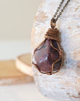 Left side view of large polished raw ruby pendant highlighting antique bronze wire wrap craftsmanship — men's statement crystal necklace, nickel-free copper wire