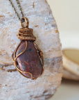 Right side view of men's large handcrafted polished raw ruby pendant showing bold antique bronze artisan wire wrapping detail