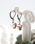 Side angle of rainbow moonstone drop earrings on a display stand, highlighting antique bronze copper wire wrapping.