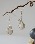 Side angle close-up of wire wrapped rainbow moonstone drop earrings highlighting pendant profile, soft silver finish, and June birthstone stone.