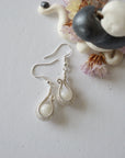 Flat lay of rainbow moonstone drop earrings showing fish hook ear wire style and handcrafted soft silver wire wrapped moonstone beads.