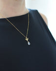 Rainbow moonstone and lotus necklace worn on a female model, faceted pear moonstone pendant with gold vermeil lotus charm on 14k gold filled chain.